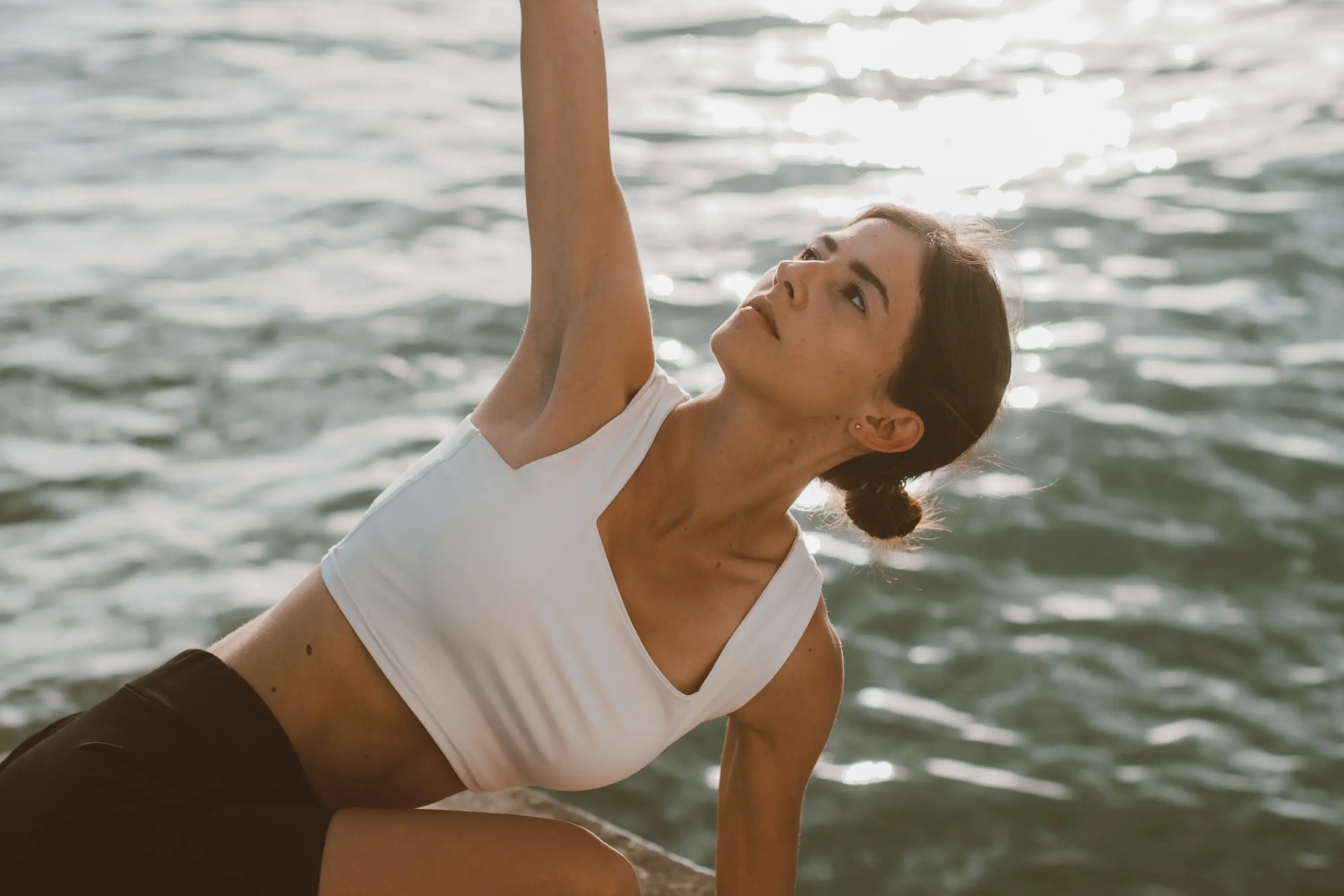 woman doing yoga outside in front of a body of water